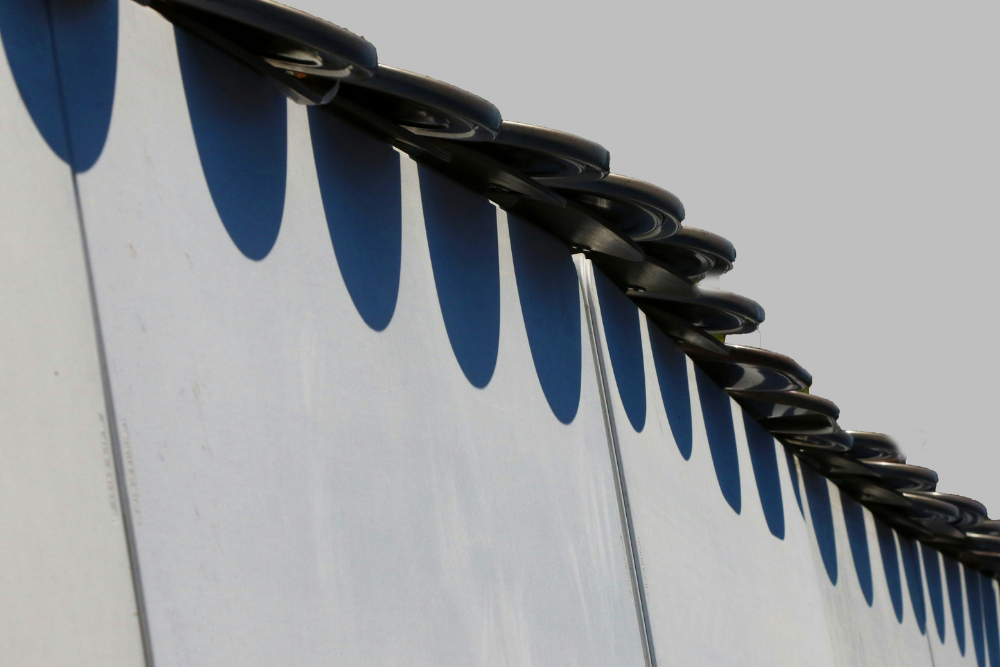 Roof edge casting shadows on a smooth wall, highlighting geometric patterns.